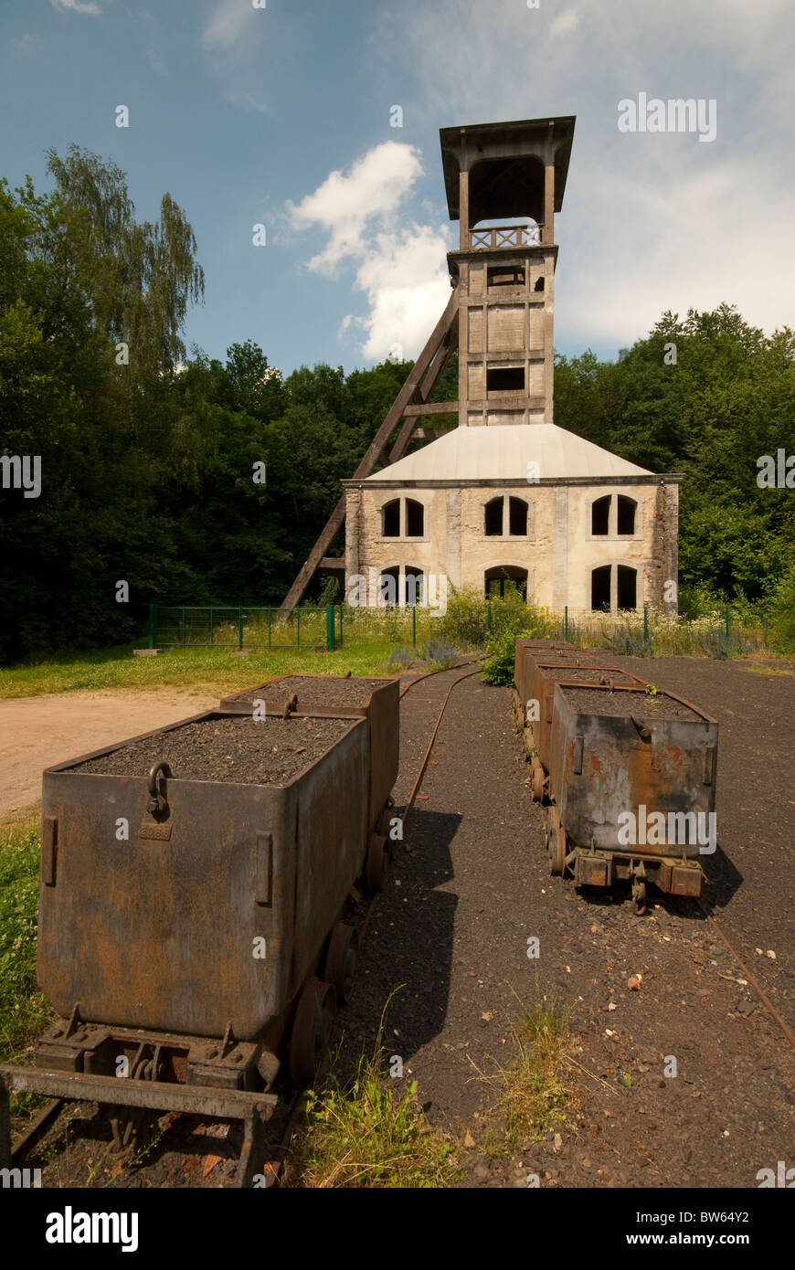 Metal ore cars from an abandoned mine stand in front of the original ventilation shaft. Stock Photo