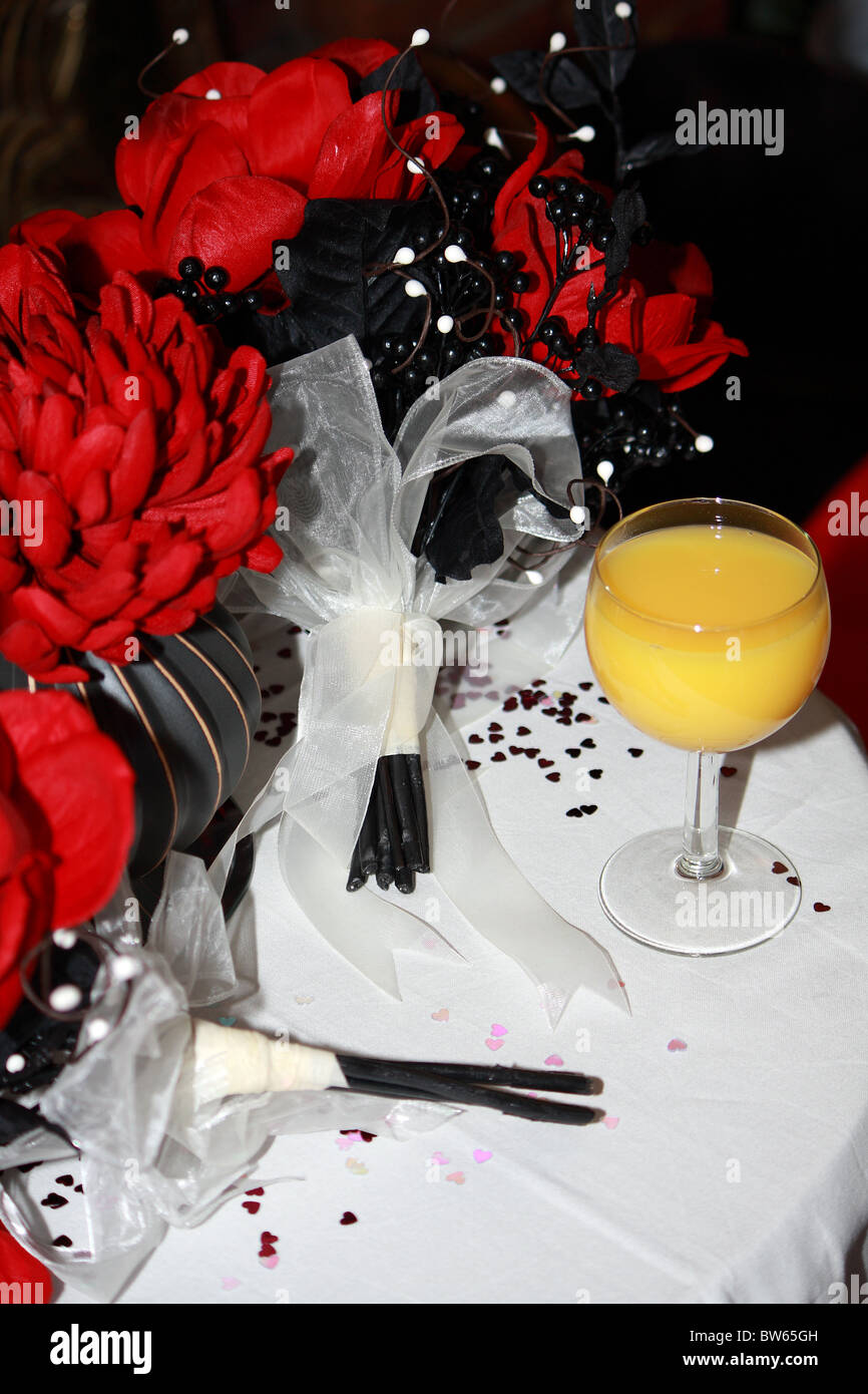 A wedding orange juice bucks fizz arrival drink next to a red flower bouquet on the arrival table Stock Photo