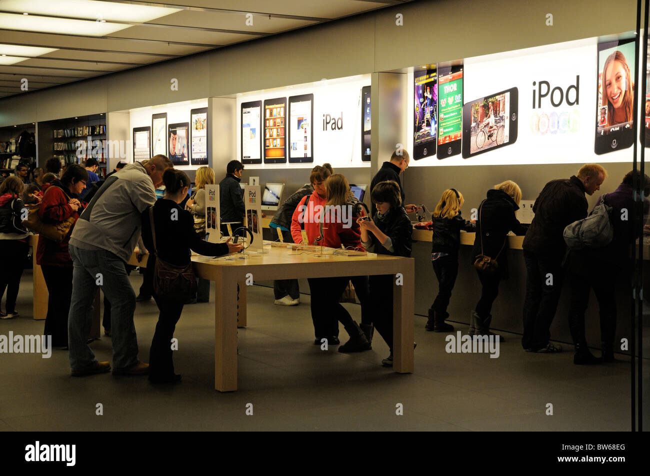 Adults & children in an Apple store checking out the iPod and iPad range of goods Stock Photo