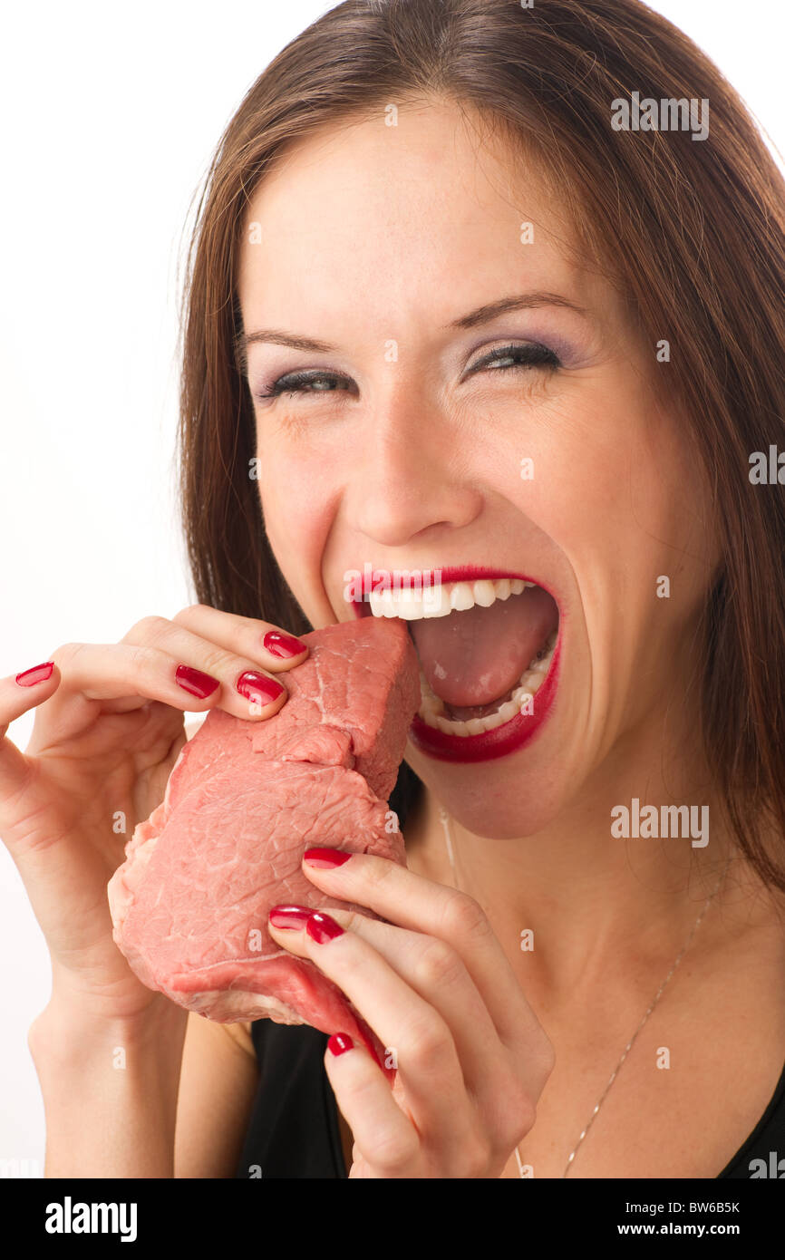 Beautiful Woman bites into a raw piece of Beef Stock Photo