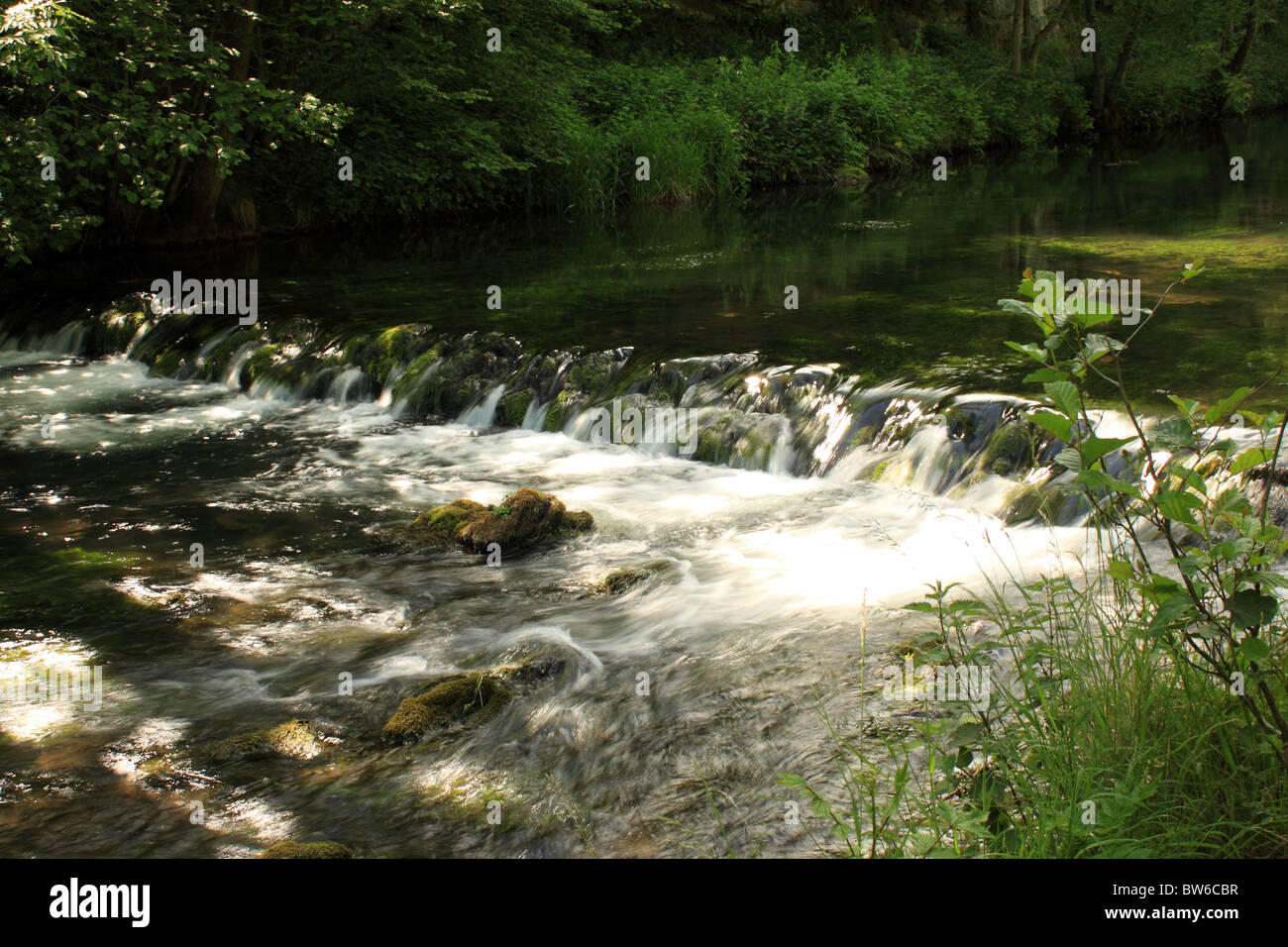 A small trench in the river dove creates a waterfall. Dovedale, Peak District UK Stock Photo