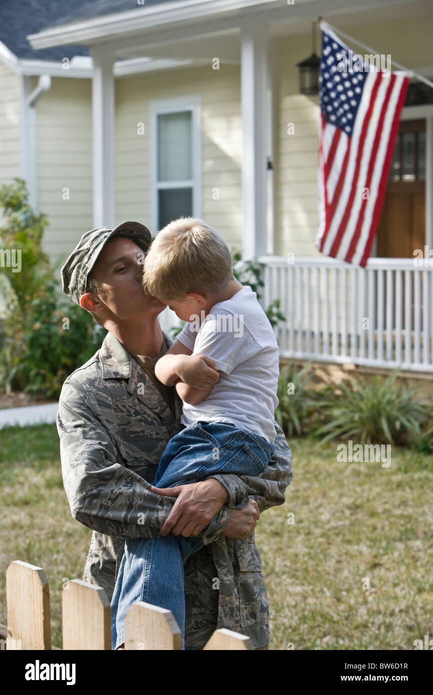 Boy and military father outside home with American Flag Stock Photo