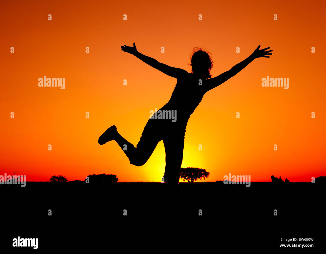 Silhouette of a young woman jumping at the sunset Stock Photo