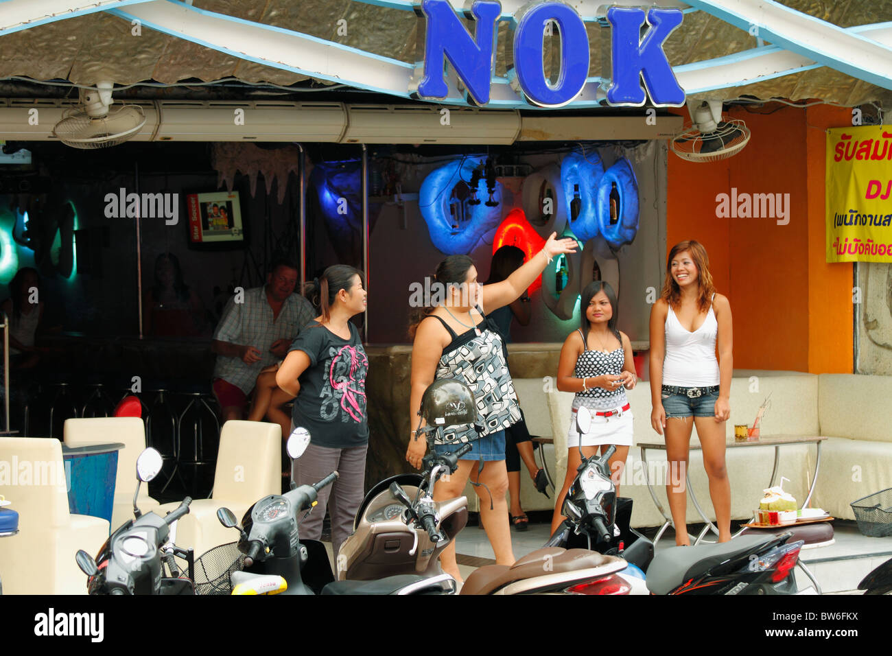 Four young Thai adult woman (girls) standing on the street, in fromt of