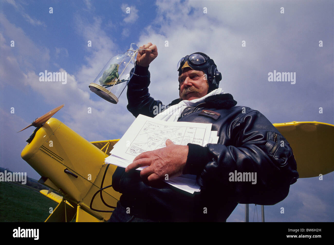 French biplane pilot checking weather forecast with a fake frog climbing a ladder in a jar (old legend for forecast) Stock Photo
