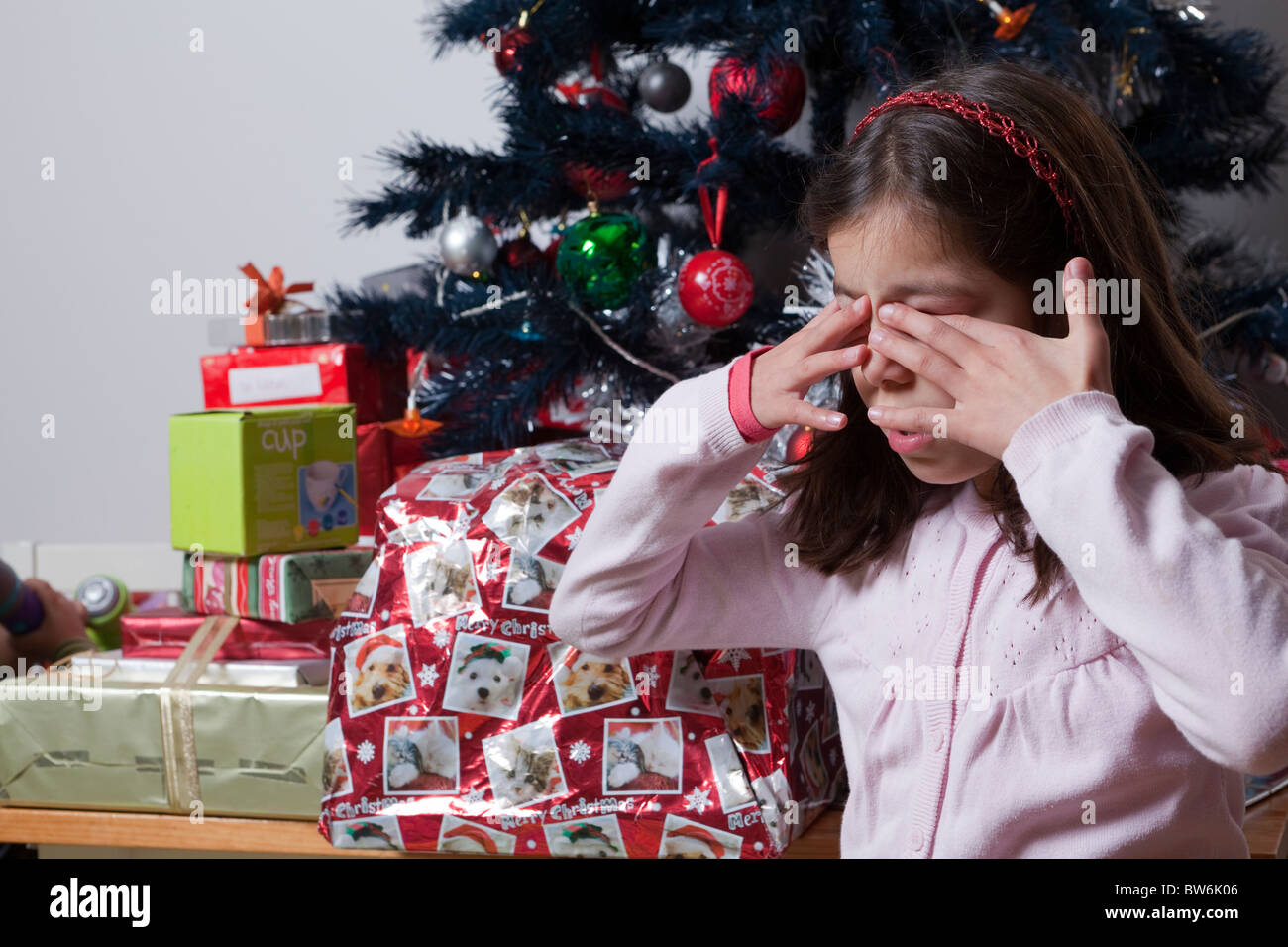Child covers her eyes waiting for surprise Christmas gift Stock Photo