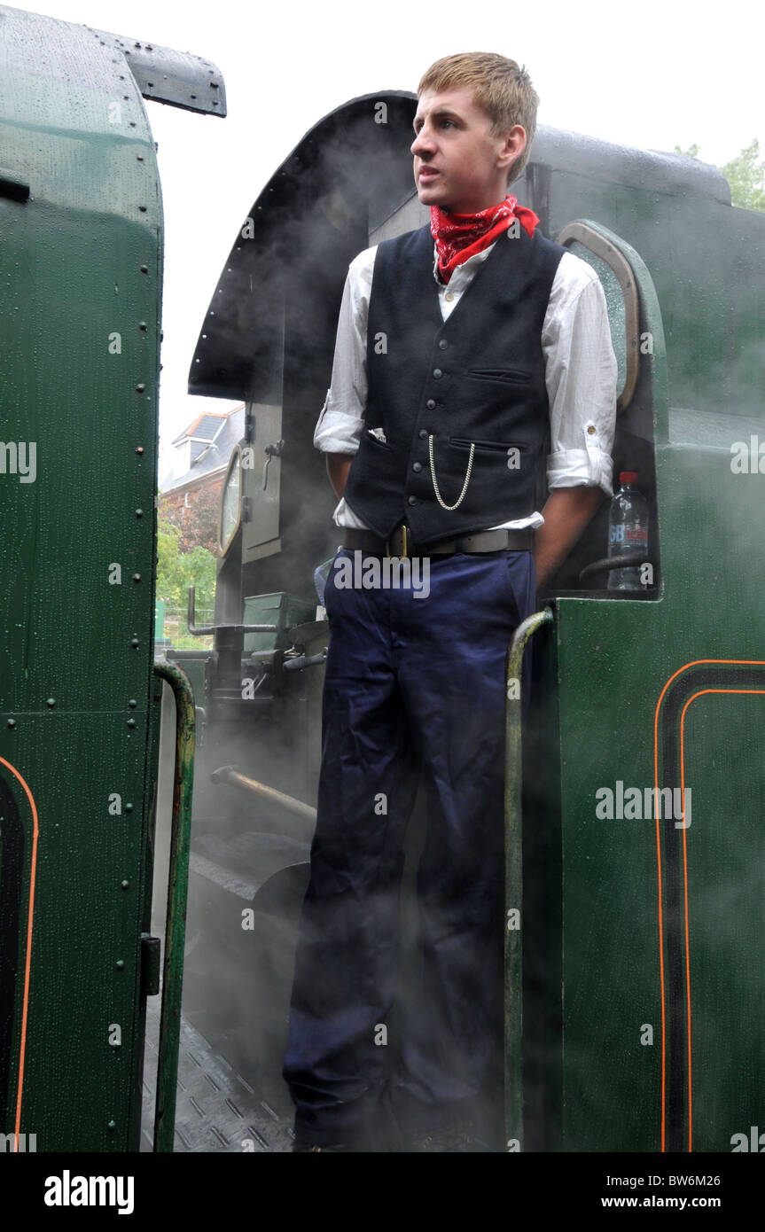 stoker standing on the engine of a steam train on the swanage railway Stock Photo