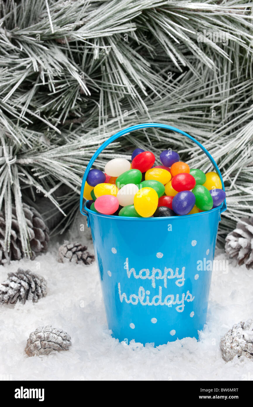 A decorative pail of Christmas candy in a snowy wilderness. Open space for copy intentionally left in the upper image tree area. Stock Photo
