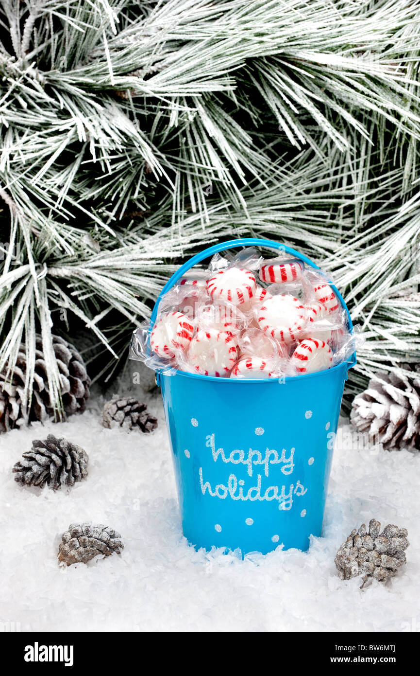 A decorative pail of Christmas candy in a snowy wilderness. Open space for copy intentionally left in the upper image tree area. Stock Photo