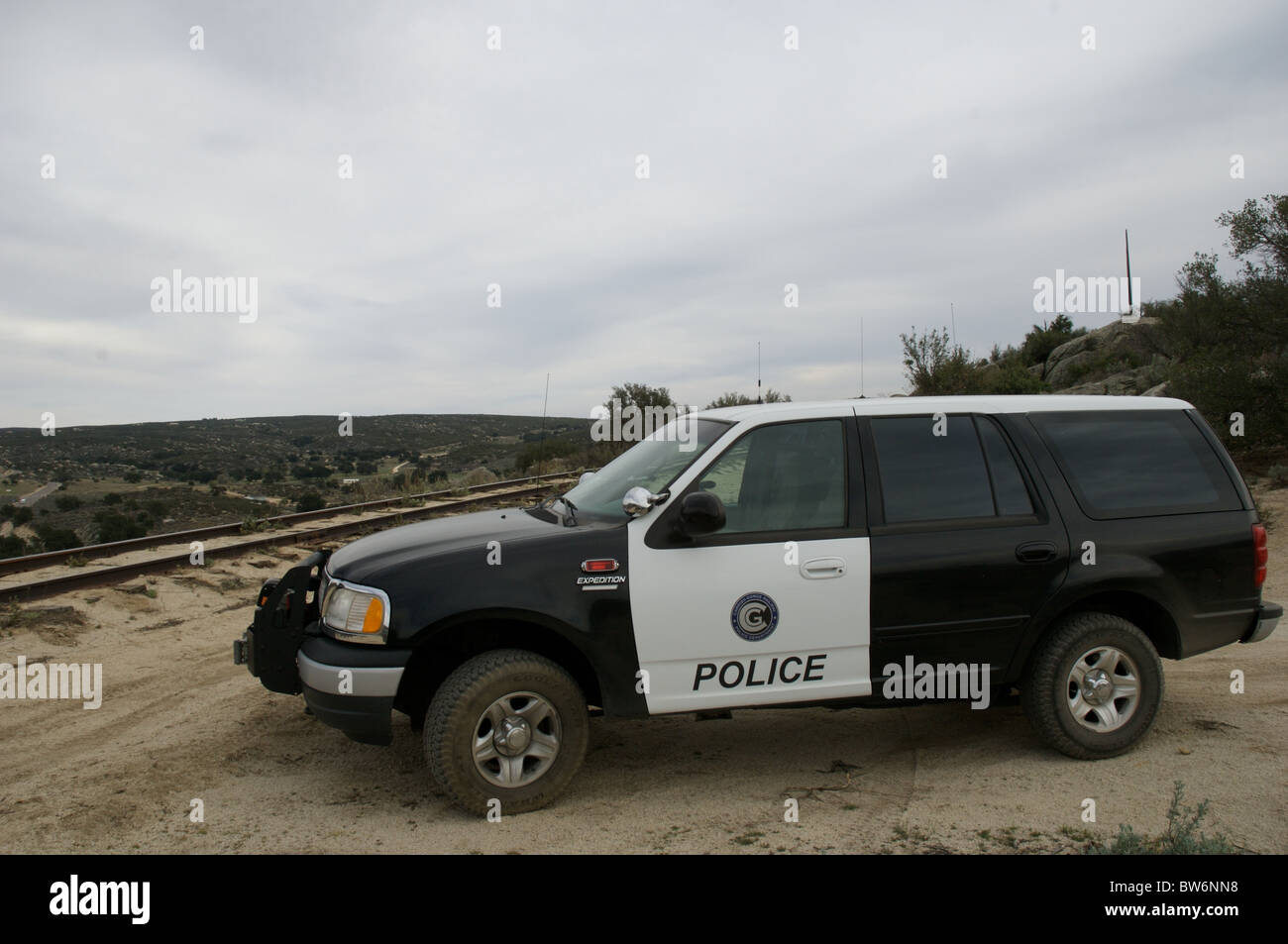 A marked railroad police vehicles stands, parked near remote desert