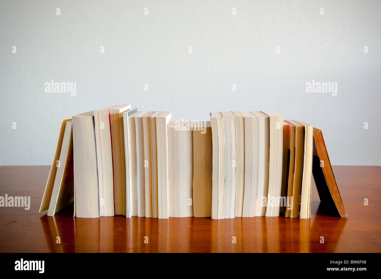 A row of books sits on a timber table with blank space behind Stock Photo
