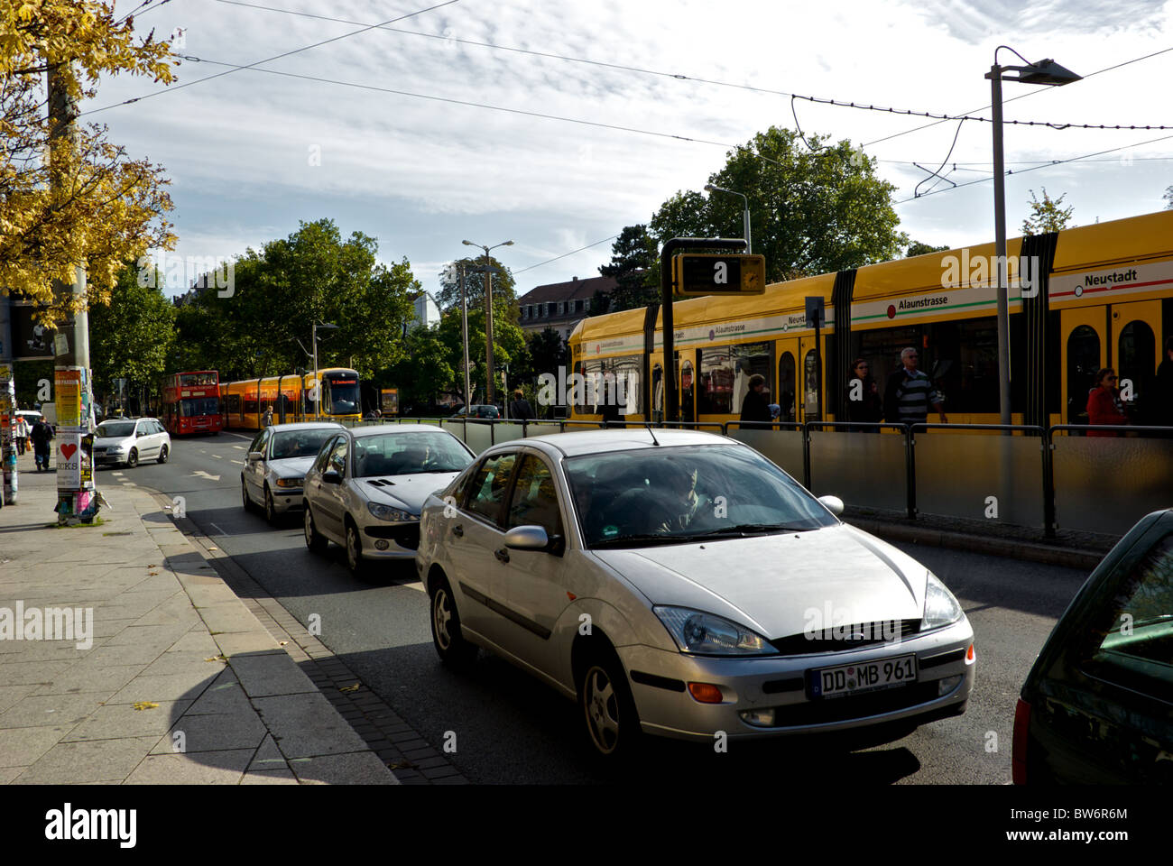 Car traffic and queue of modern electric articulated commuter trams at