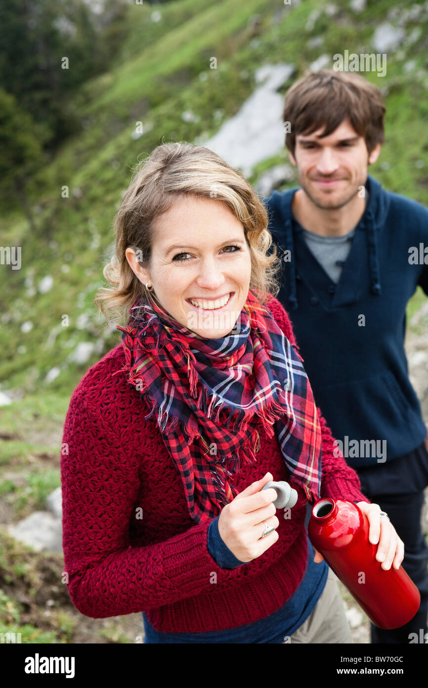 Woman holding bottle man in background Stock Photo