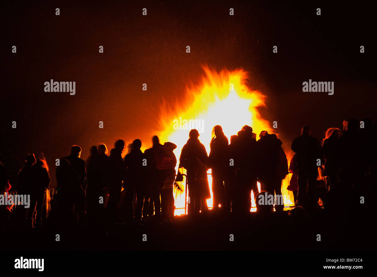Festivals, Guy Fawkes, Bonfire, People silhouetted by flames from fire on the beach. Stock Photo