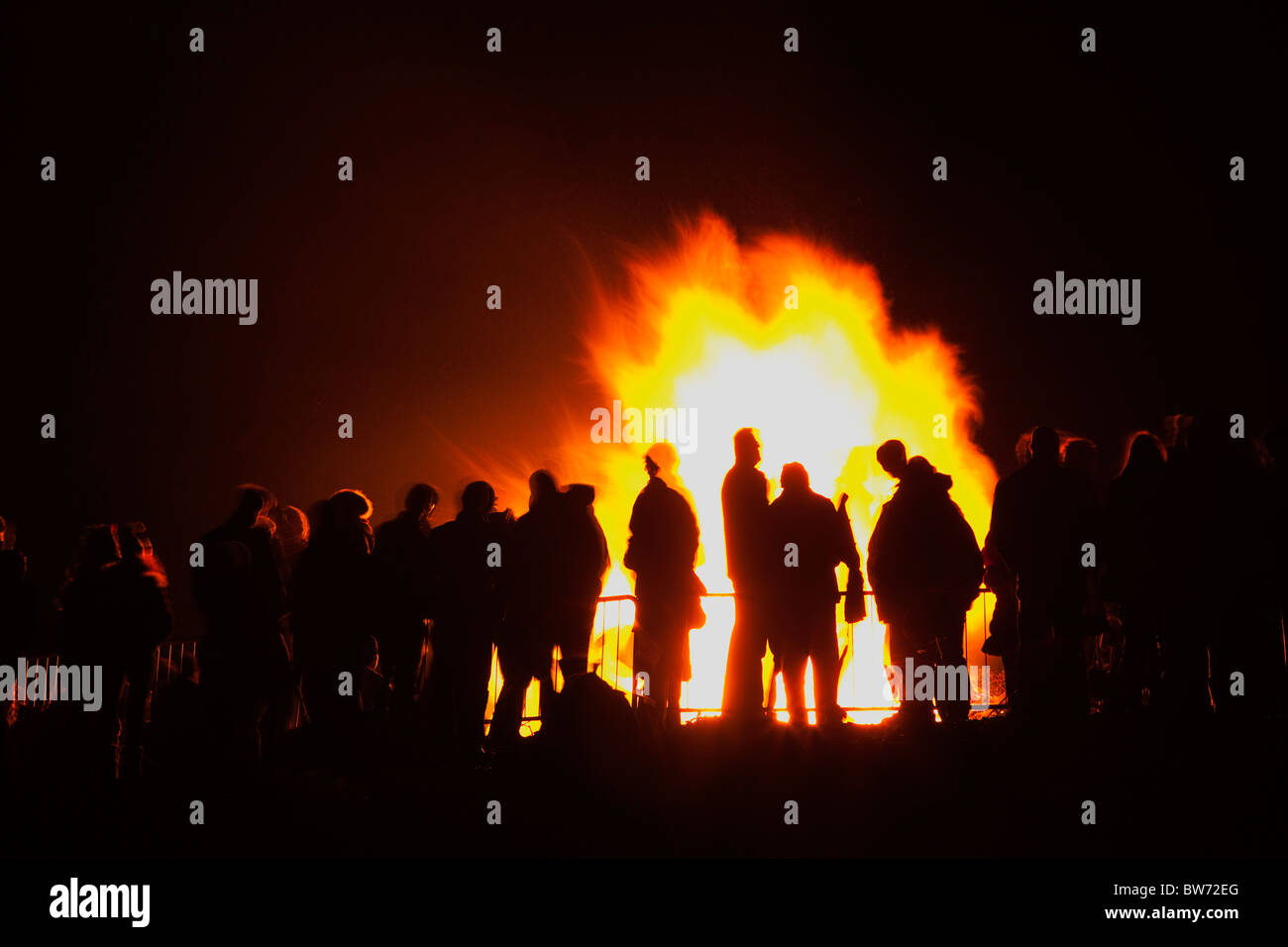 Festivals, Guy Fawkes, Bonfire, People silhouetted by flames from fire on the beach. Stock Photo