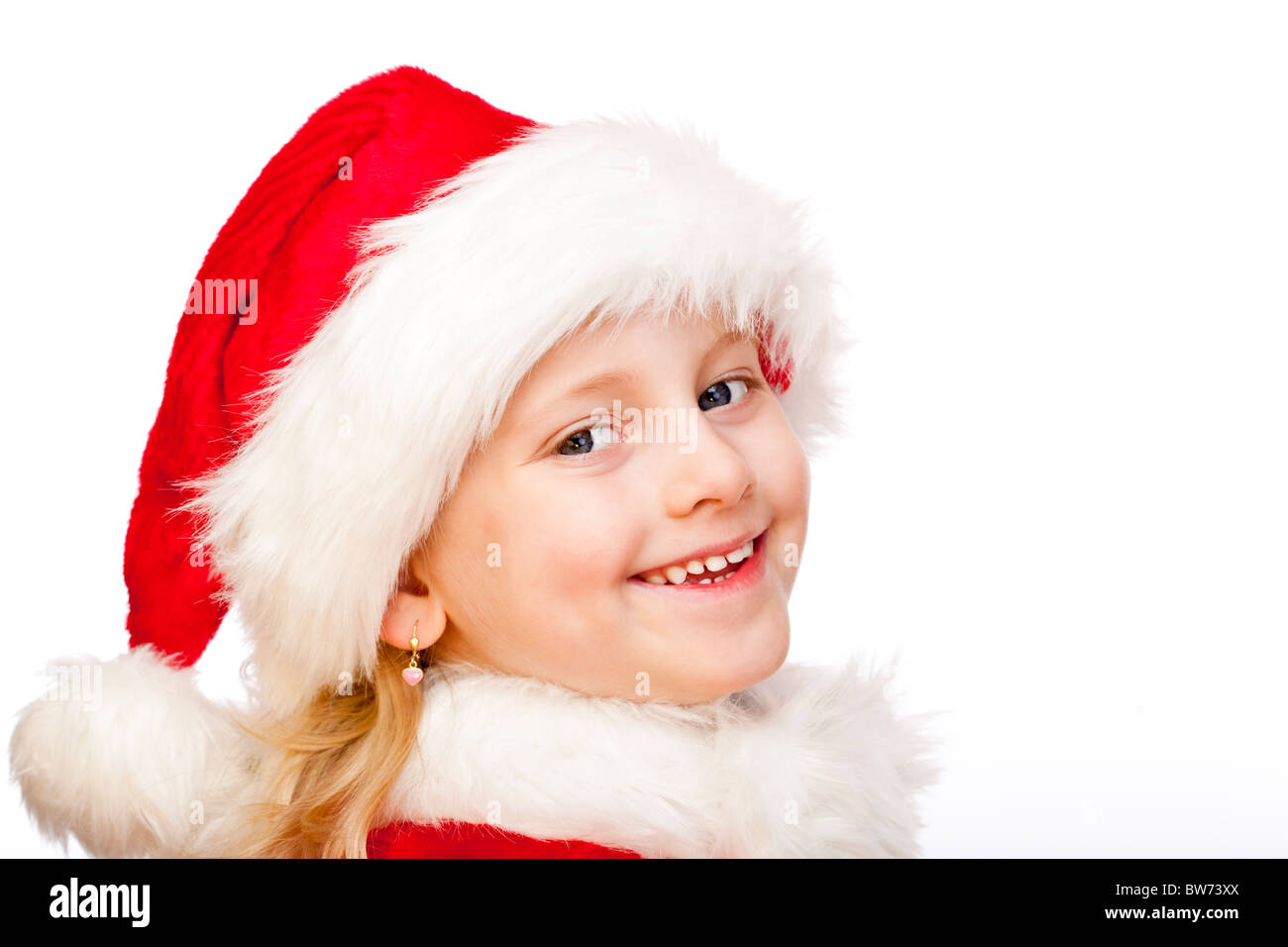 Small girl dressed as Santa Claus smiles happy into camera. Isolated on white background. Stock Photo