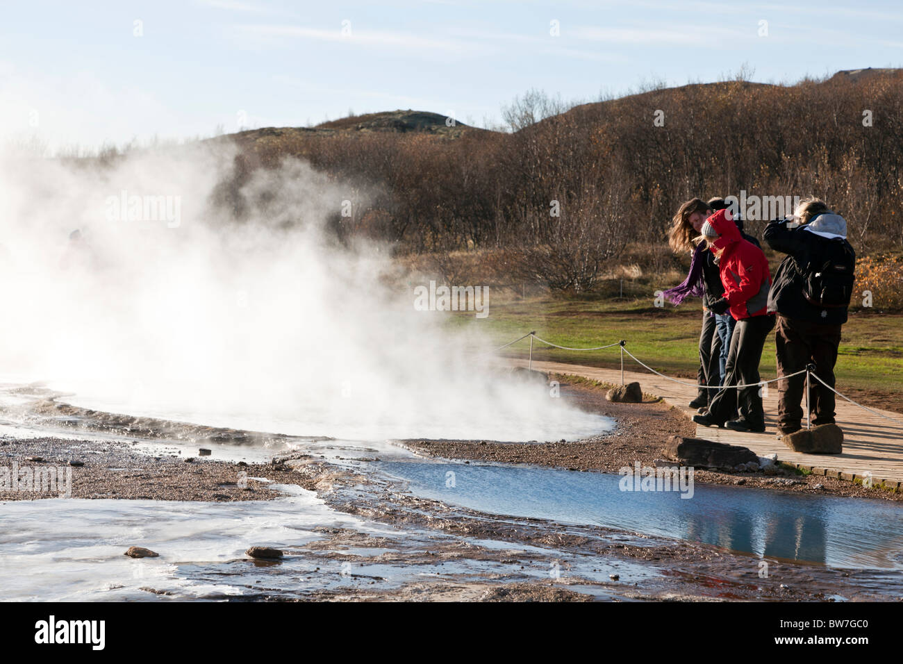 Tourists watching the eruption of a geyser in southwest Iceland. Stock Photo