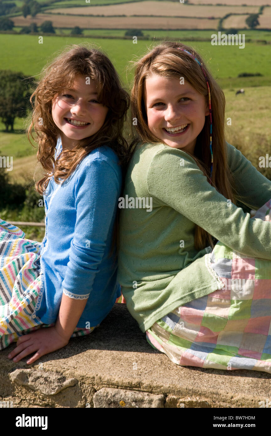 Portrait of two girls sitting back to back Stock Photo - Alamy