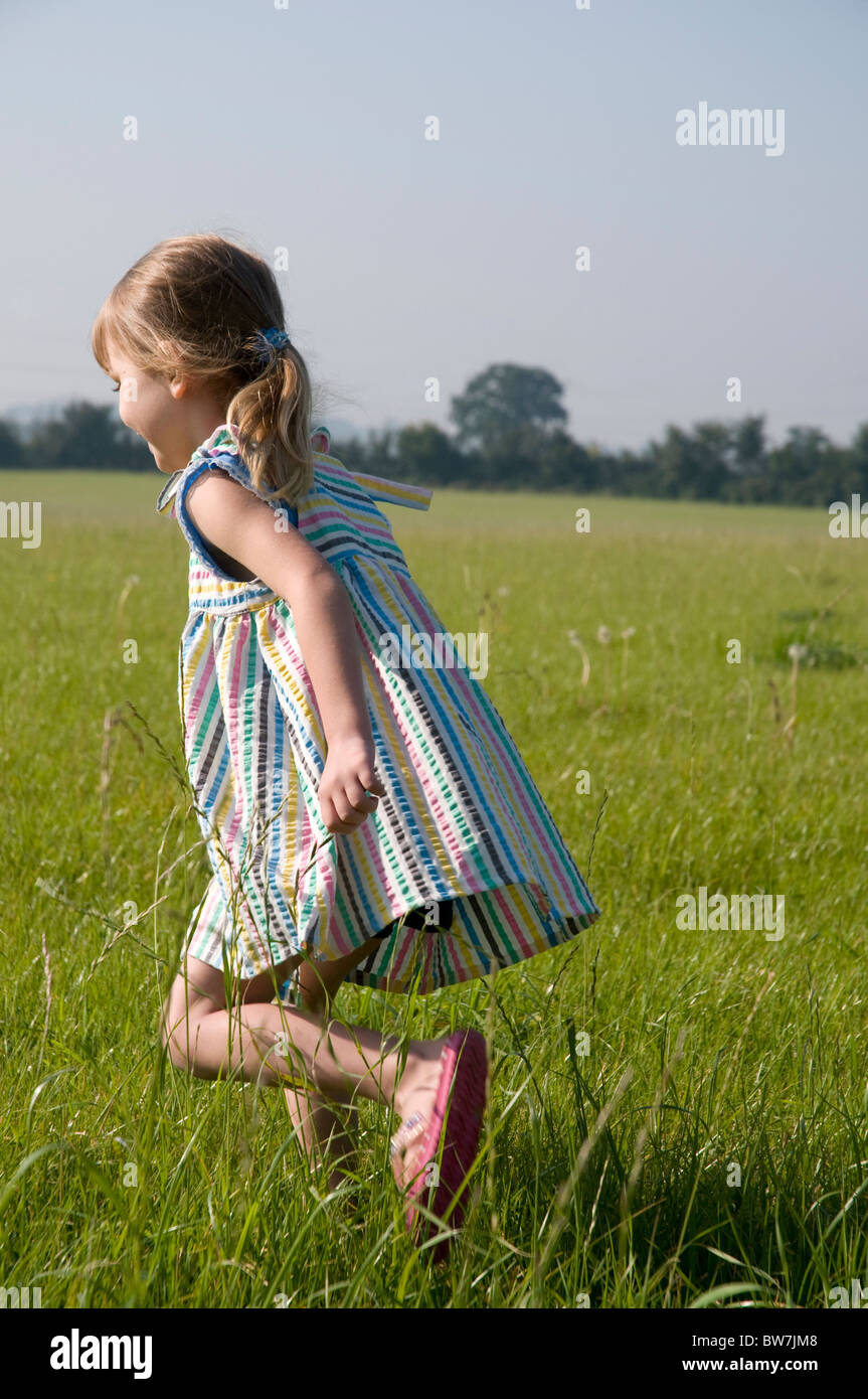 Little girl running through a meadow wearing a summer dress Stock Photo