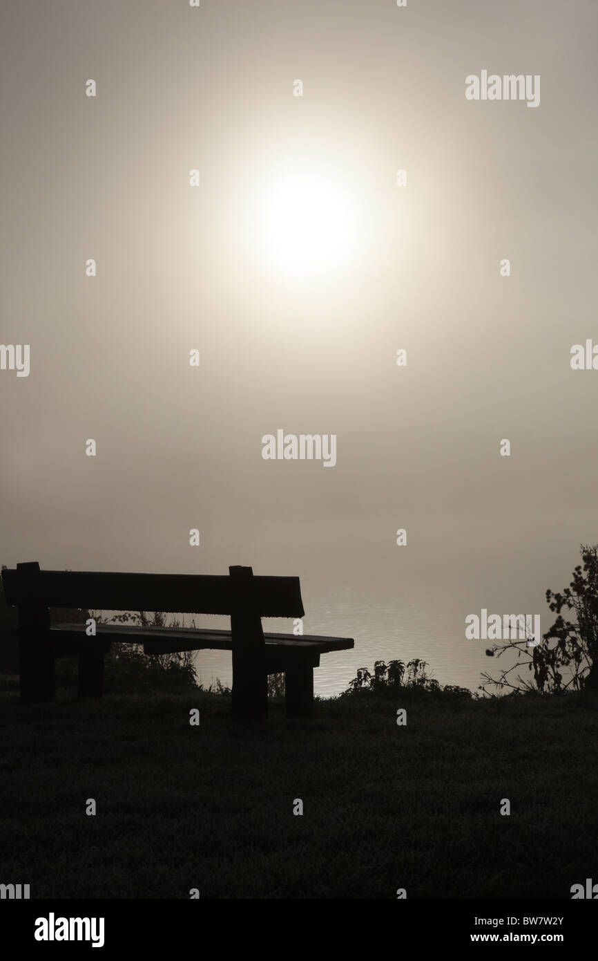 Empty bench looking across a misty expanse Stock Photo
