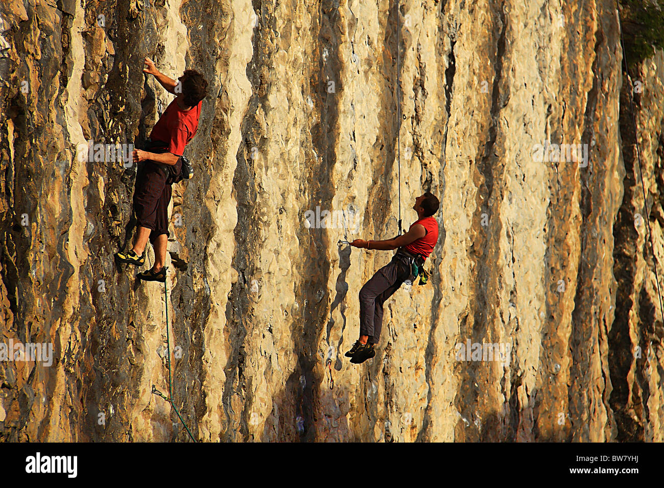 Two climbers, training on a climbing wall, faces a difficult passage