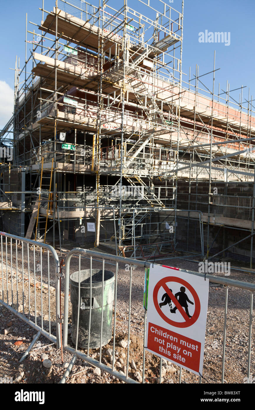 scaffolding covering new building under construction with warning sign children must not play on this site Stock Photo