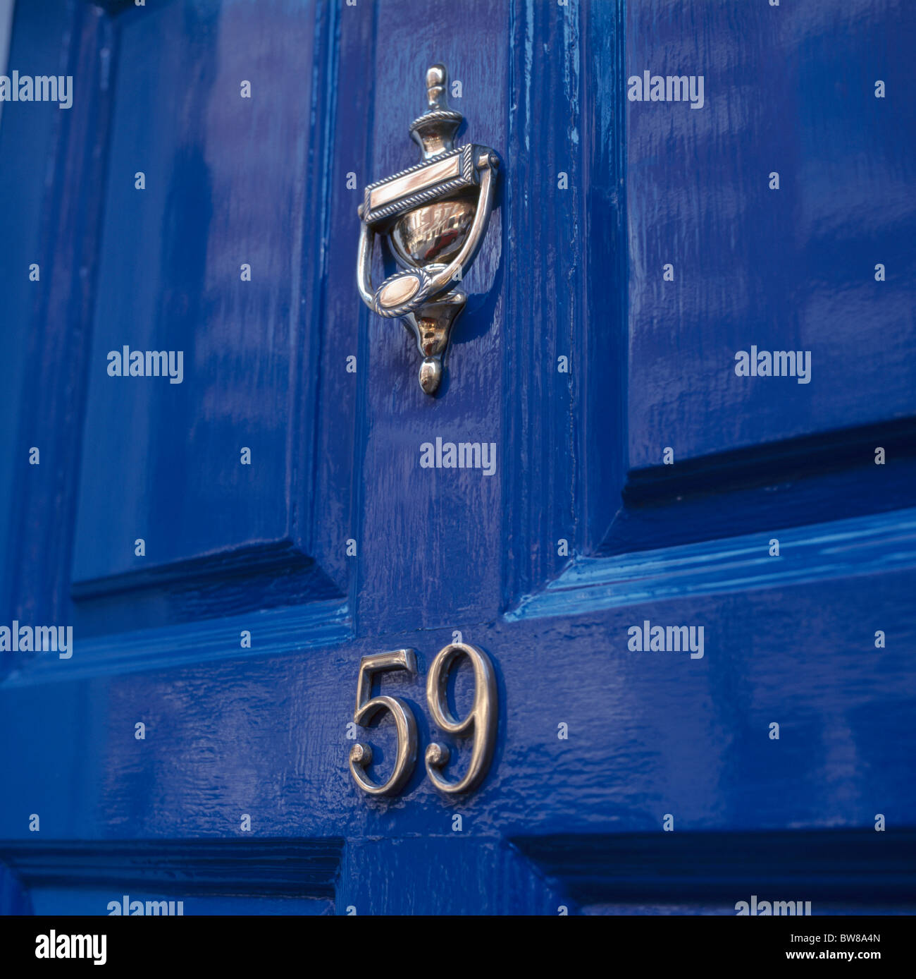 Close-up of brass knocker and house number on bright blue painted front door Stock Photo