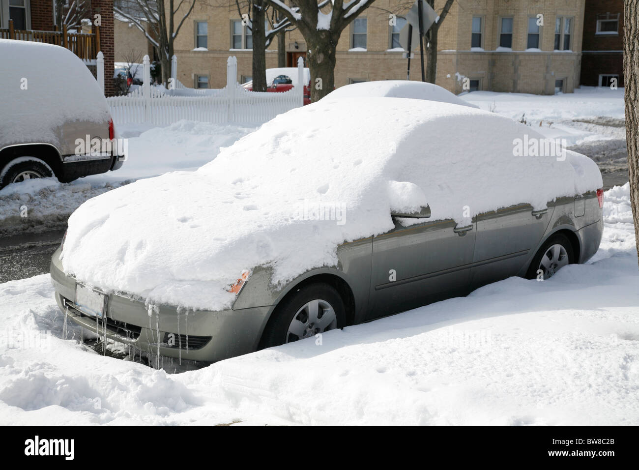 snow covers and surrounds a car parked on a city street in winter Stock ...