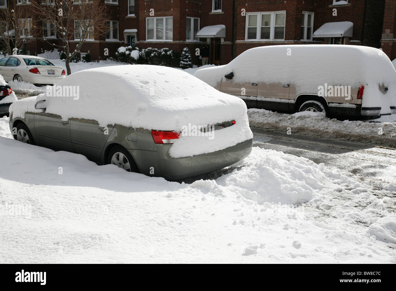 snow covers and surrounds a car and truck parked on a street in winter ...