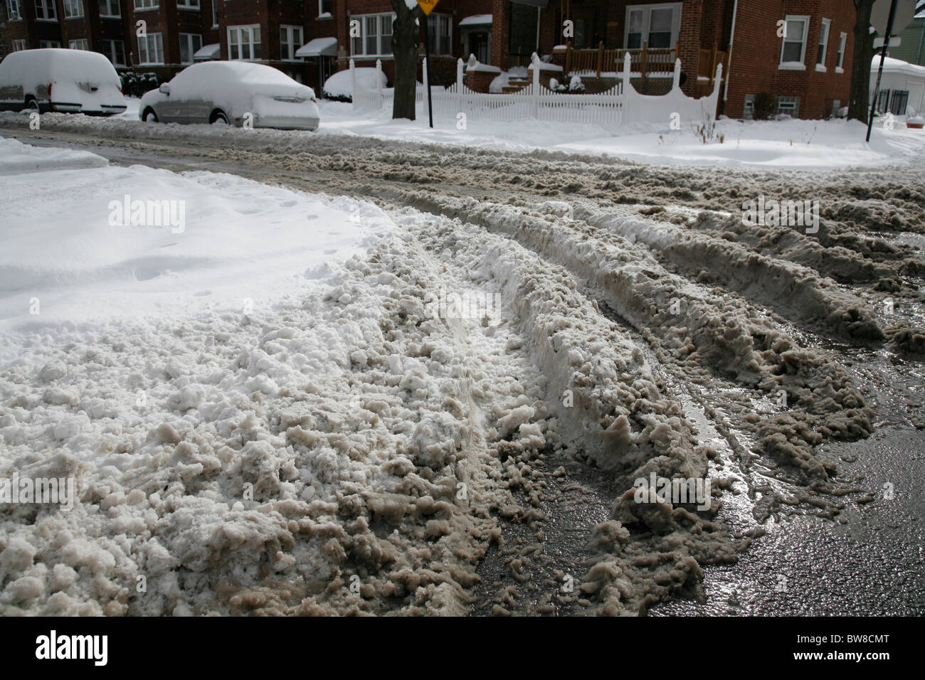 dirty snow on a plowed city side street with tire tracks in winter ...