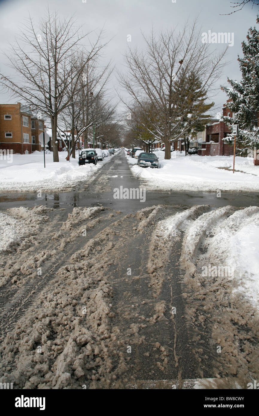 dirty wet snow and tire tracks on a plowed city side street intersection in winter Stock Photo