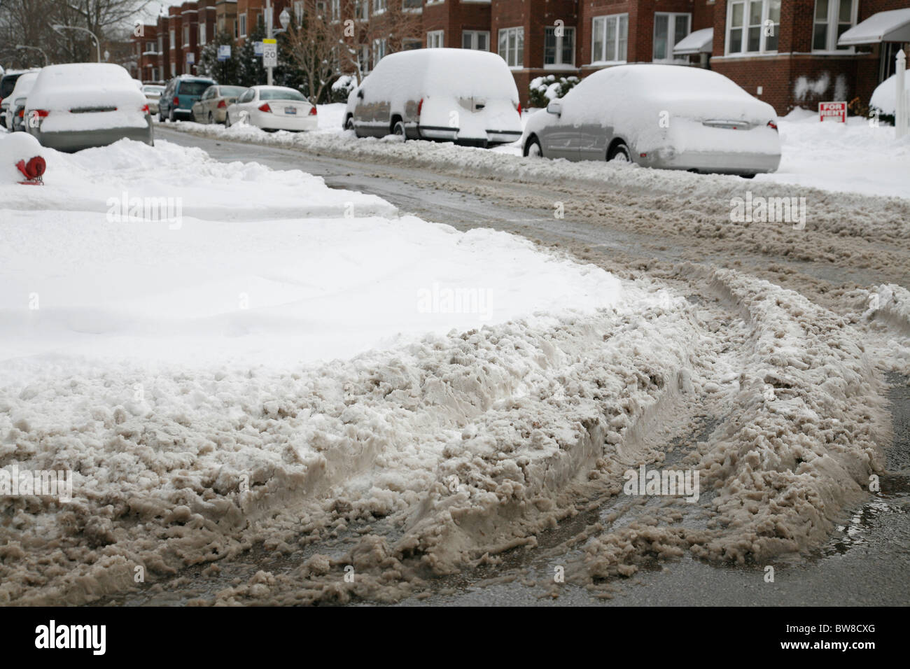 dirty snow and tire tracks on a plowed city street intersection in ...