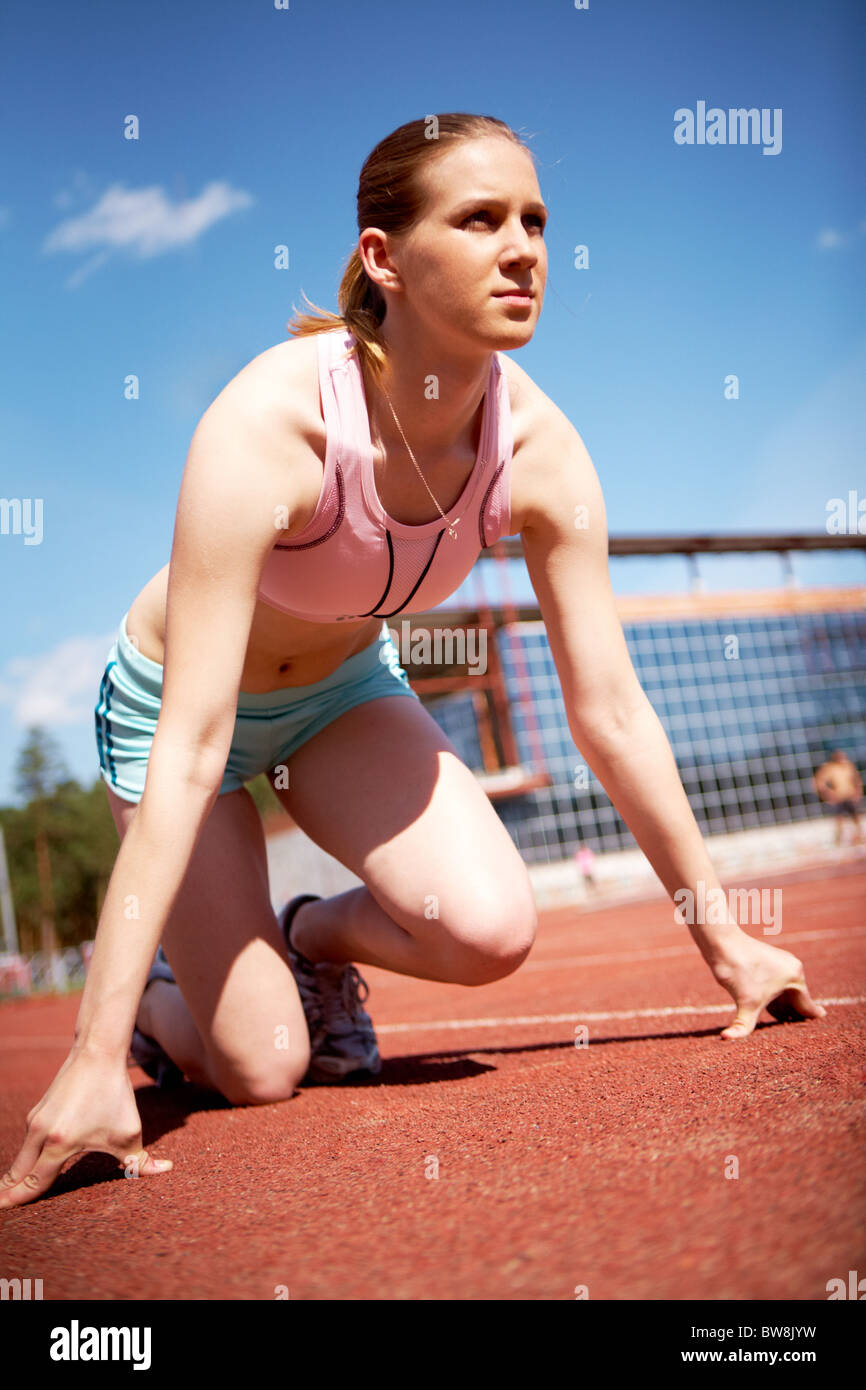 Image of young female ready to start running while on stadium Stock Photo
