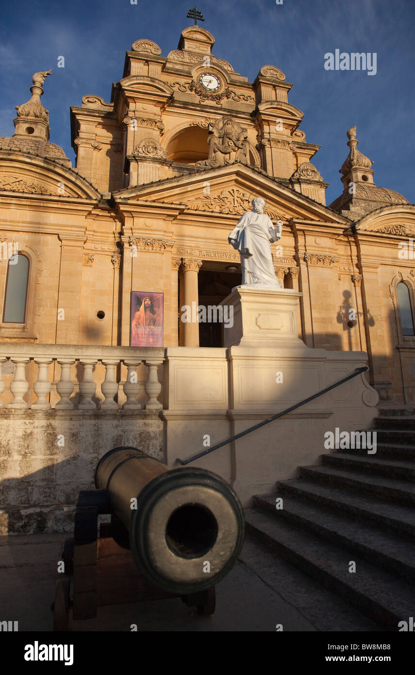 A medieval cannon outside the ornate baroque parish church in Nadur in Gozo in Malta. Stock Photo