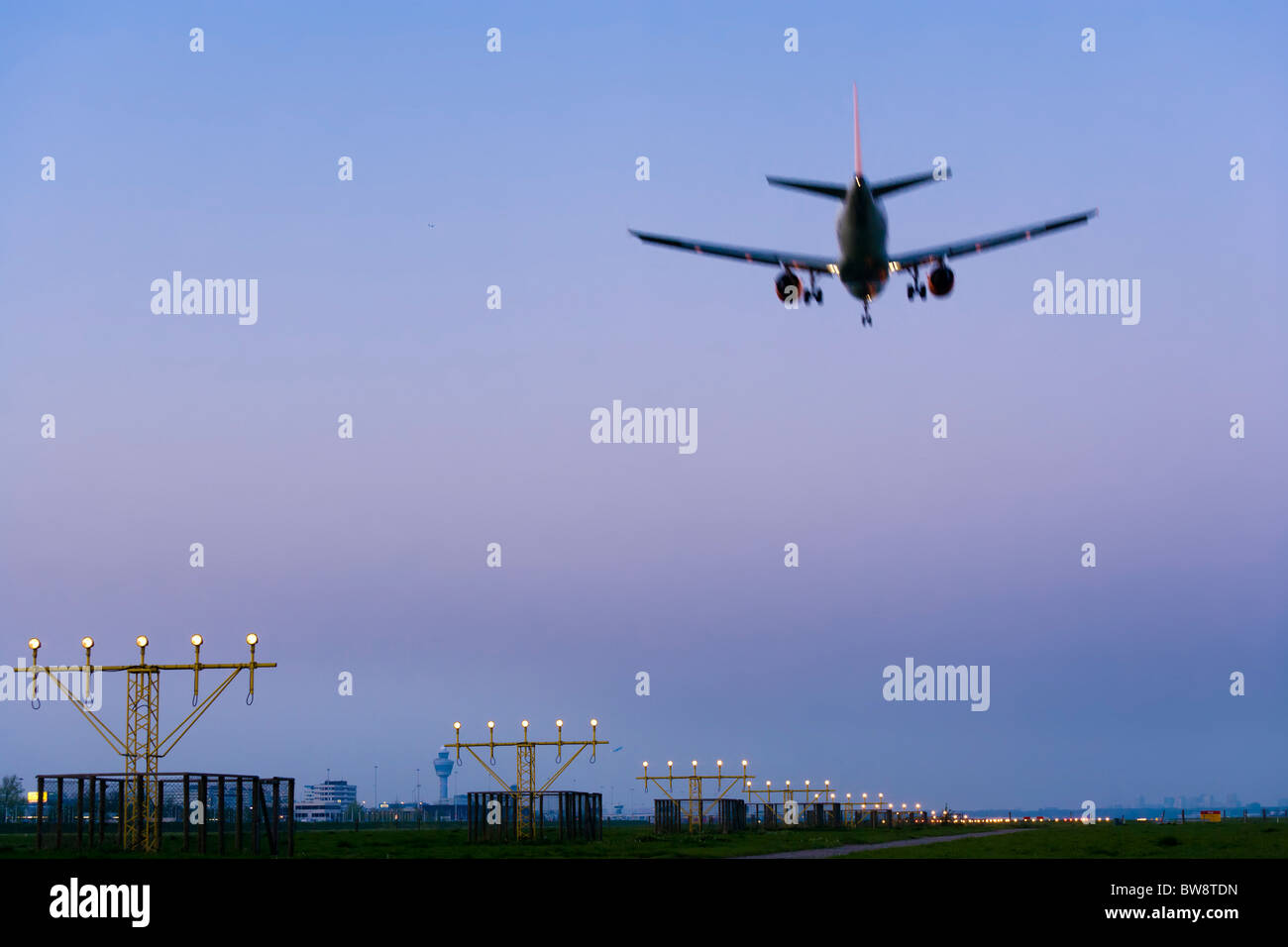 Amsterdam Schiphol Airport at dusk. Airplane plane approaching, landing, on the Kaagbaan runway. Stock Photo