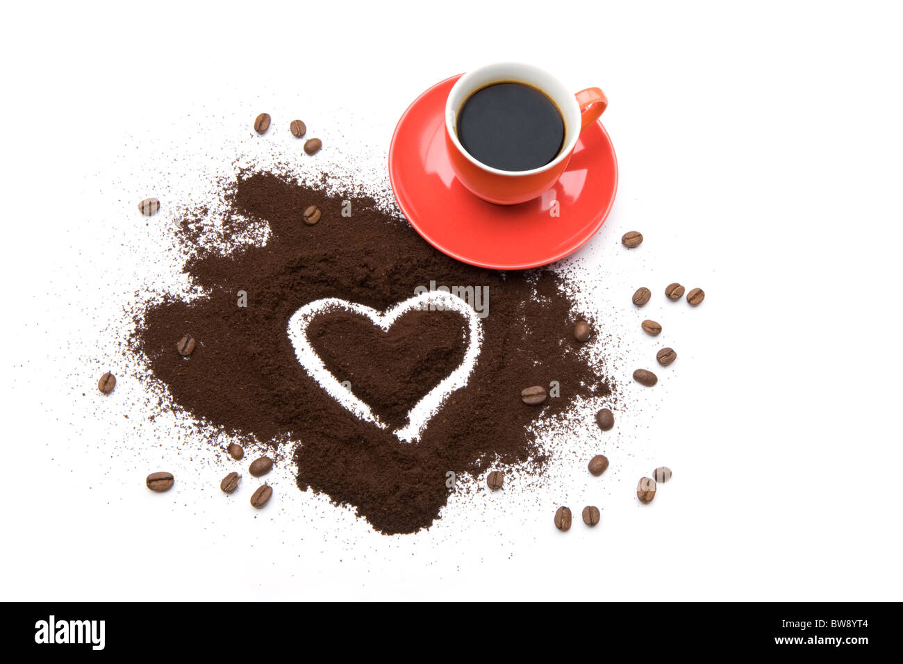 Photo of cup of coffee with shape of heart drawn in ground coffee near