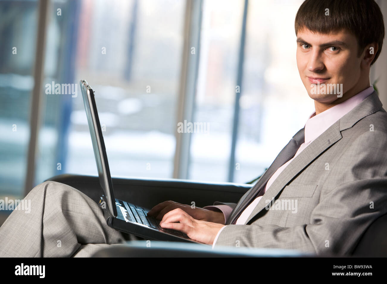 Handsome male typing on keyboard of laptop and looking at camera Stock ...