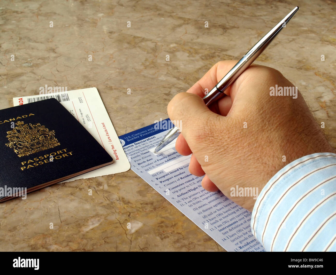 Man filling out U.S. customs and border form with Canadian Passport Stock Photo