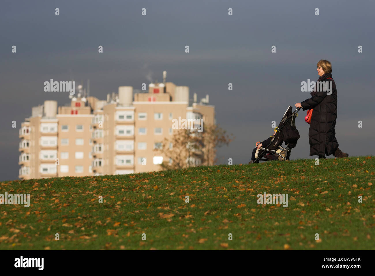 Grandmother and child on bike with high-rise flats seen from Brockwell Park, Herne Hill, South London. Stock Photo