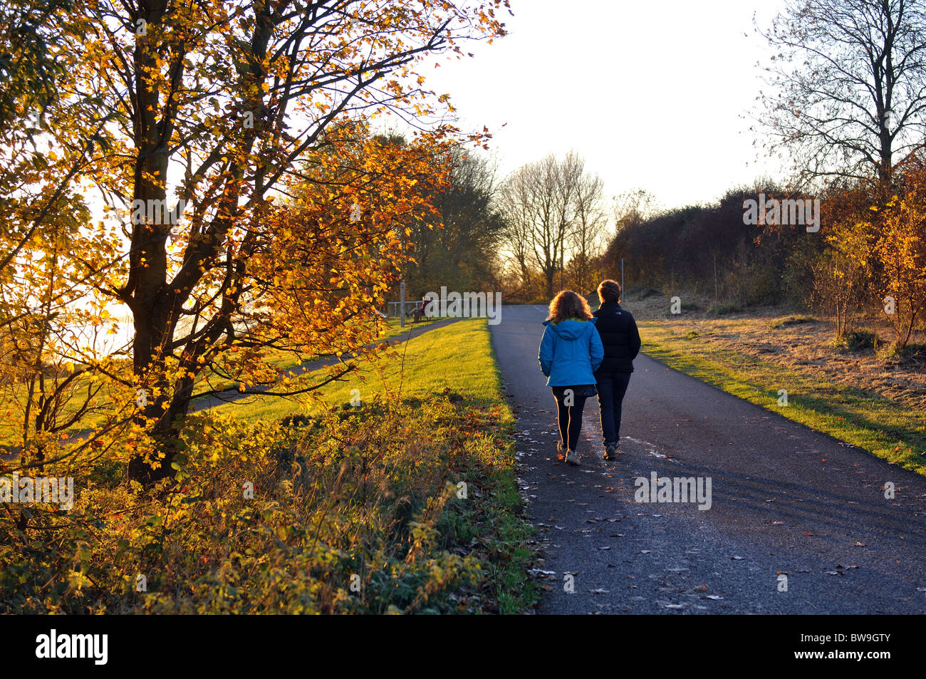 People walking on perimeter path of Draycote Water in autumn, Warwickshire, UK Stock Photo