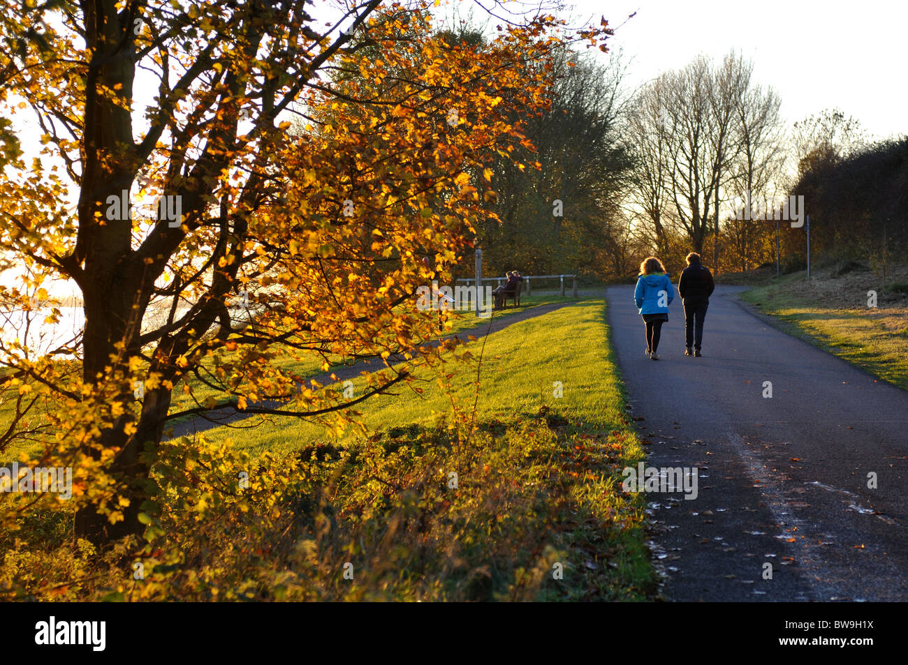 People walking on perimeter path of Draycote Water in autumn, Warwickshire, UK Stock Photo
