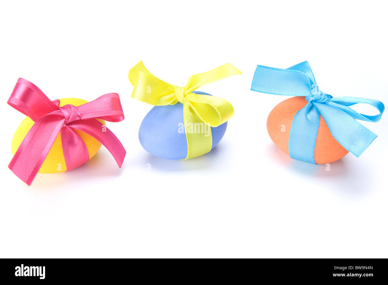 Image of three multicolored eggs tied by silk ribbons on white background Stock Photo