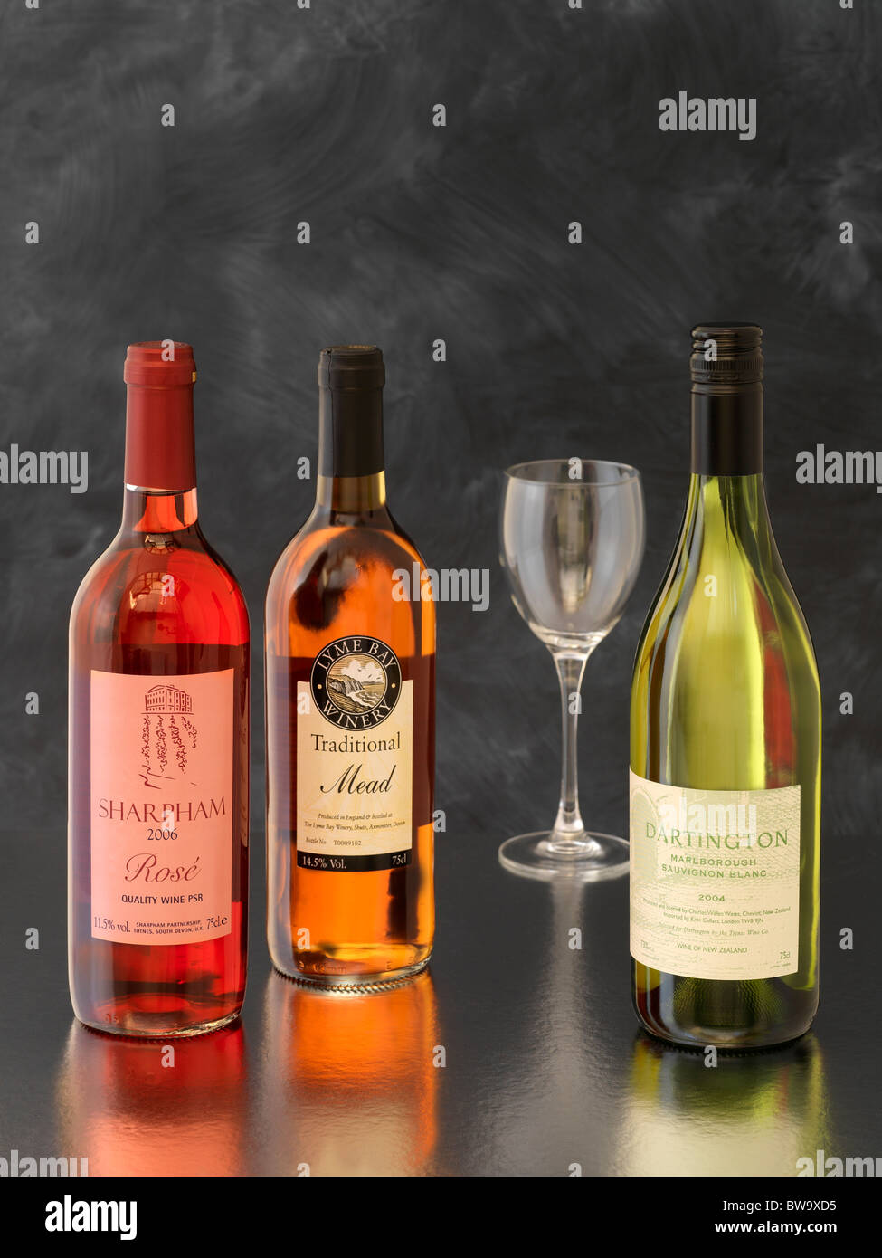 Three bottles of English wine and a wine glass on grey background Stock Photo