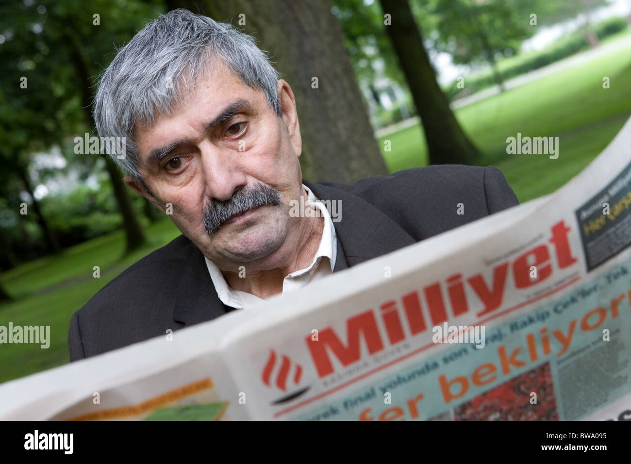 Older turkish man reads a newspaper, Herne, Germany Stock Photo