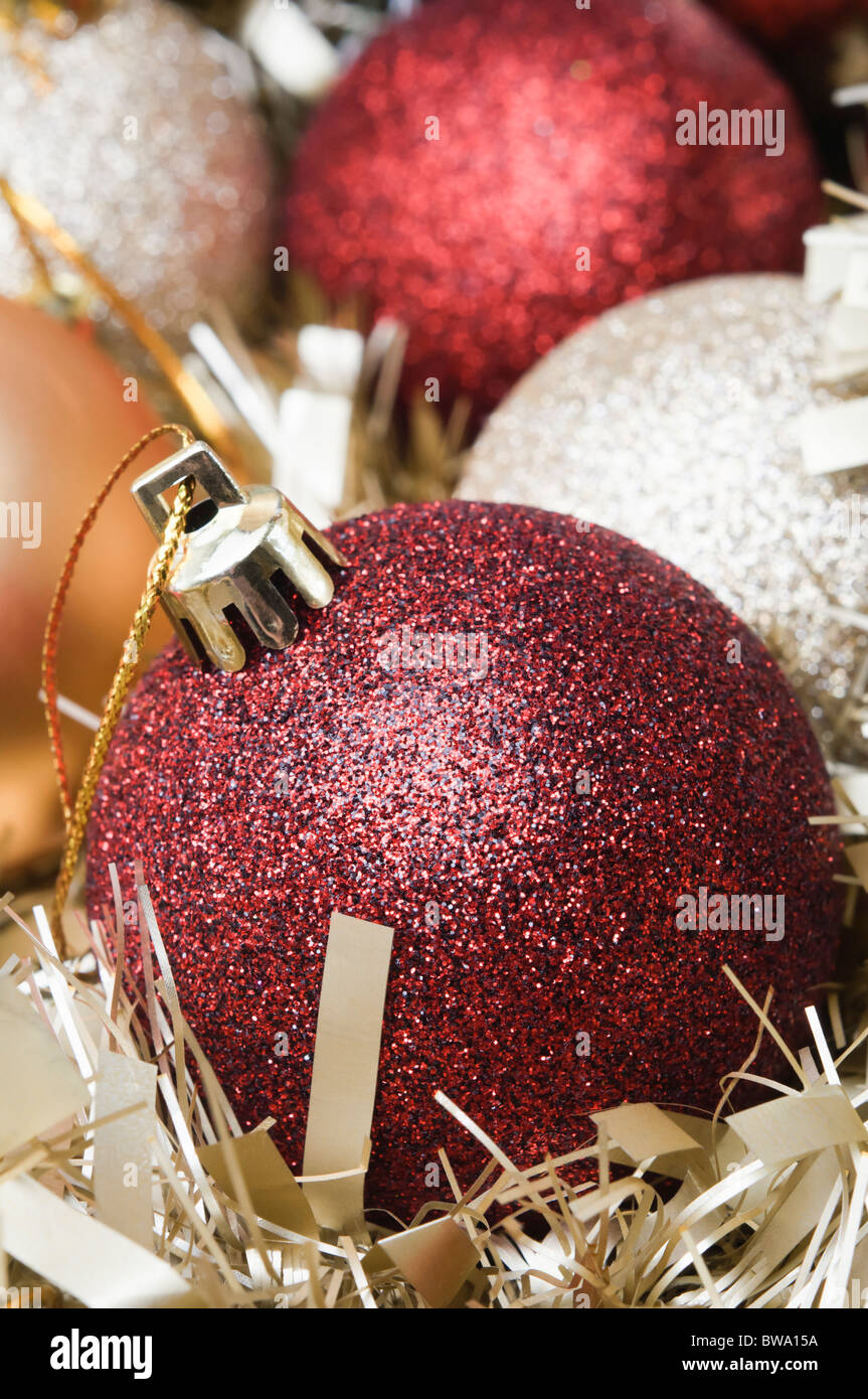 Red, silver and gold Christmas baubles nestling in gold tinsel. Vertical orientation. Stock Photo