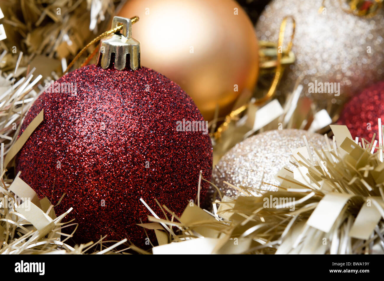 Christmas baubles nestling in gold tinsel garland. Horizontal