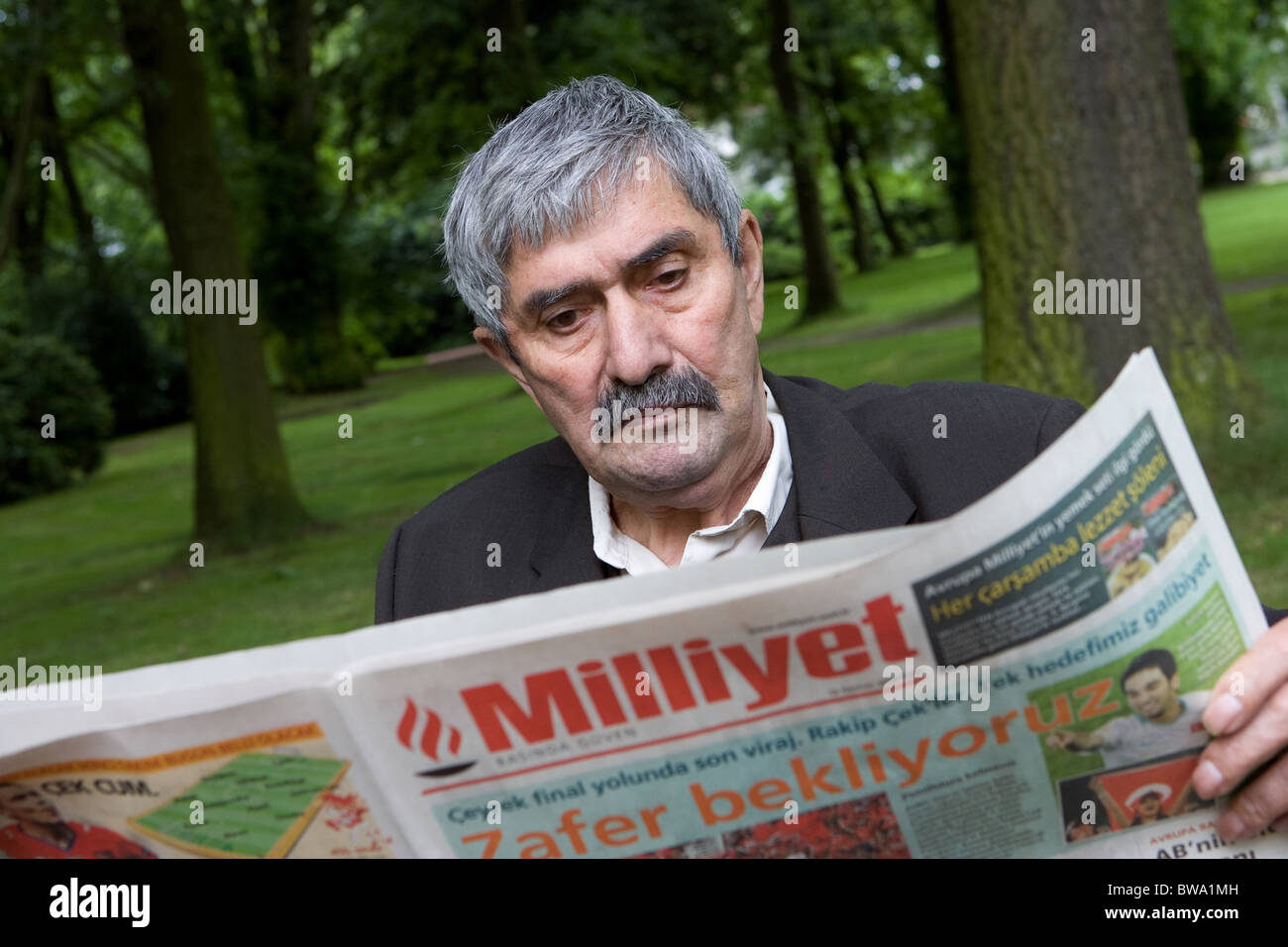 An elderly Turkish man reading a newspaper, Herne, Germany Stock Photo