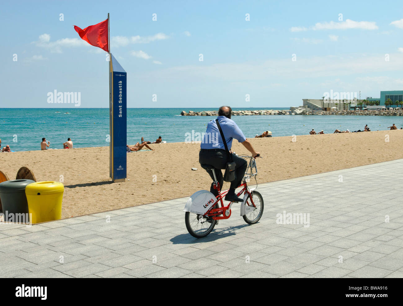 man riding BICING bike-sharing bicycle on Passeig Maritim de la Barceloneta near San Sebastá nude beach in Barcelona Stock Photo