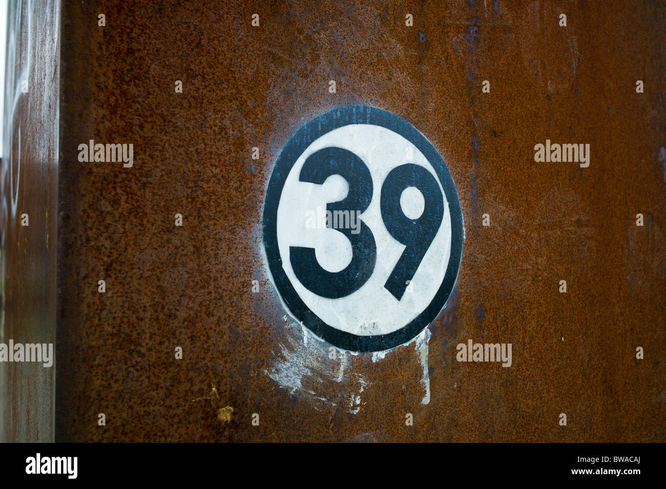 Black number 39 on white background within a black circle spray painted on rusty steel, Berlin, Gernany Stock Photo