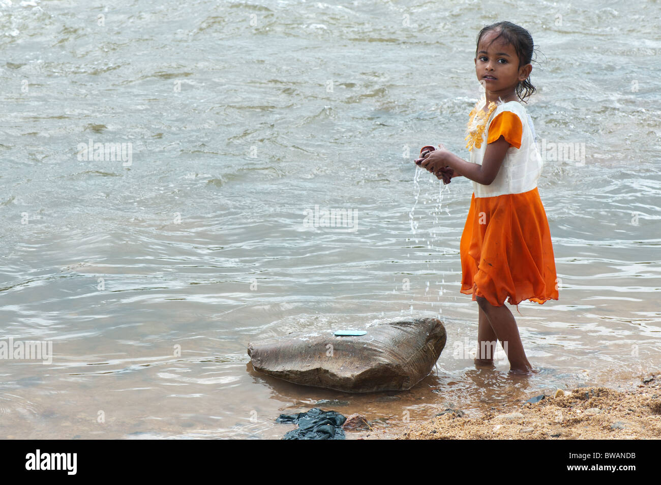 Young Indian girl washing clothes by hand on a stone in the river